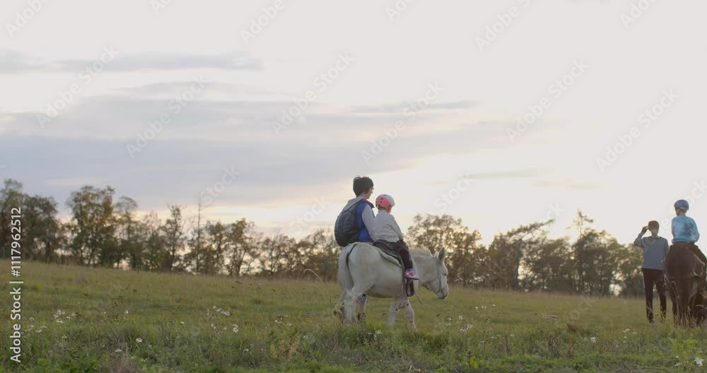 Two children happily enjoy a peaceful ride together on a horse in a stunningly beautiful field during sunset Cz, Svarov, 29.10.24 Two children happily enjoy a peaceful ride together on a horse in a stunningly beautiful field during sunset Cz, Svarov, 29.10.24