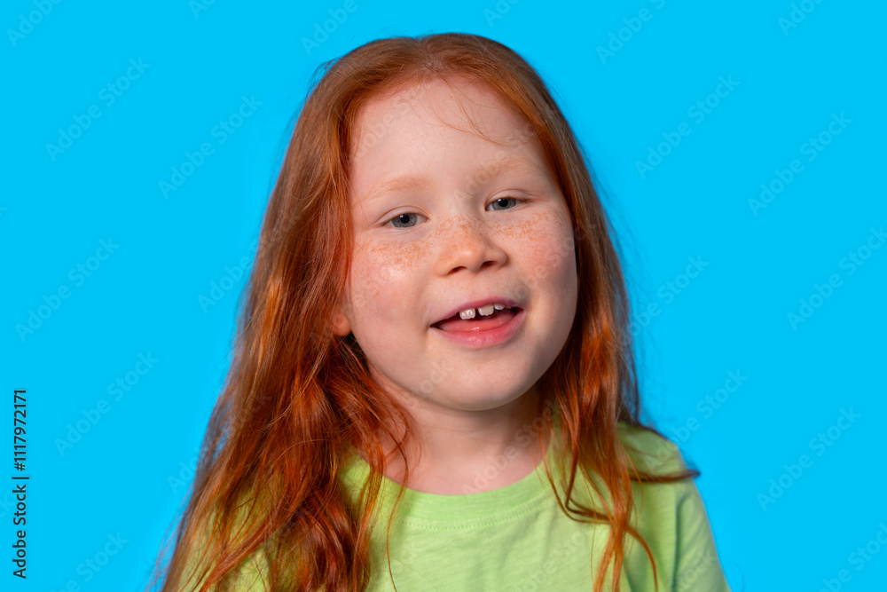 Young girl with red hair smiling against a bright blue background during the day Young girl with red hair smiling against a bright blue background during the day