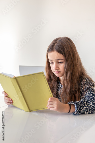 Sad girl reading a book at home. Girl student teaches lessons to school.