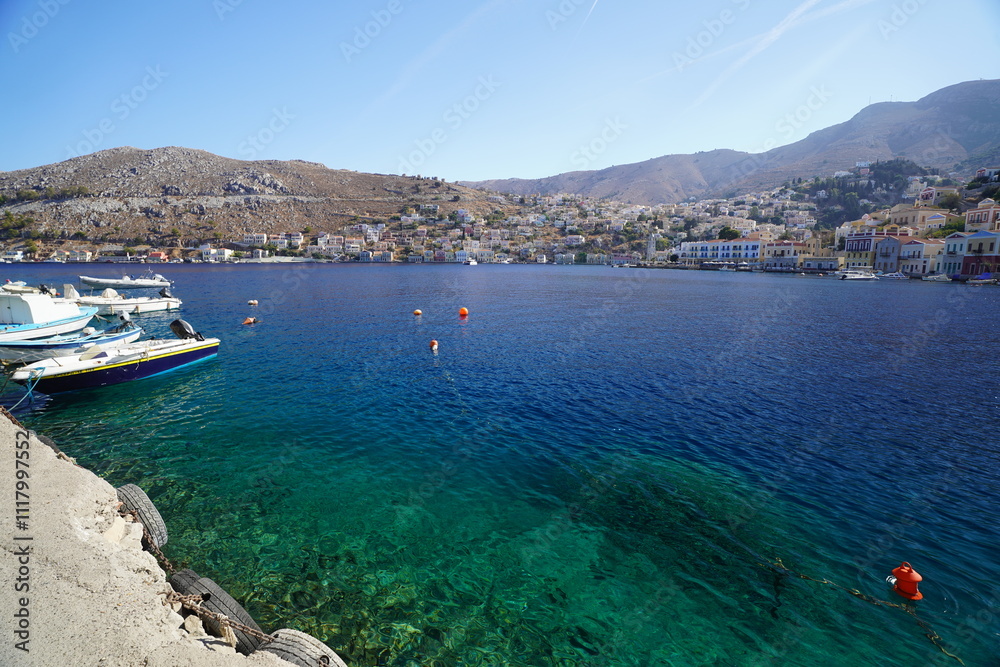 Naklejka premium boats in turquoise clear water on Symi island port