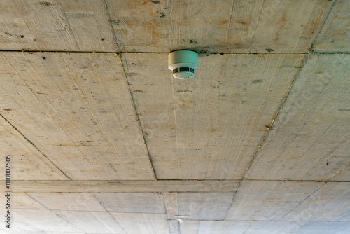 Concrete ceiling in an underground parking garage with carbon monoxide detectors mounted at the ceiling to trigger an alarm if the gas concentration is getting too high.
