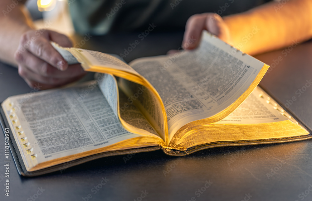 Fototapeta premium A man reads the Bible. Male hands on the Holy Bible. Close-up of the Bible.