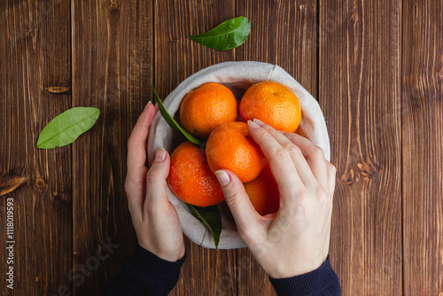 Tangerines in a straw basket on a brown wooden table.