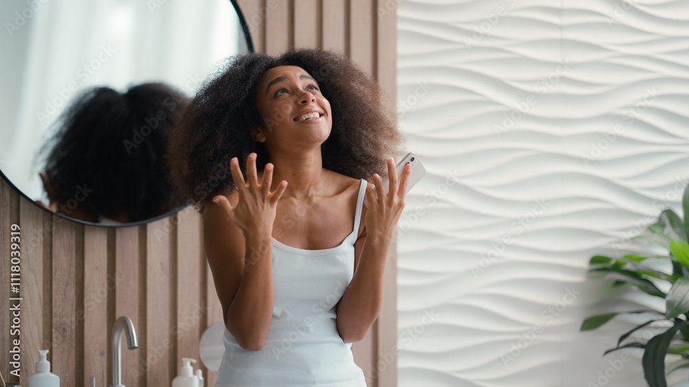 Fototapeta premium Excited female at home achievement with smartphone amazing news result offer happy African American girl woman mobile phone win victory successful yelling rejoice celebrate winning online in bathroom