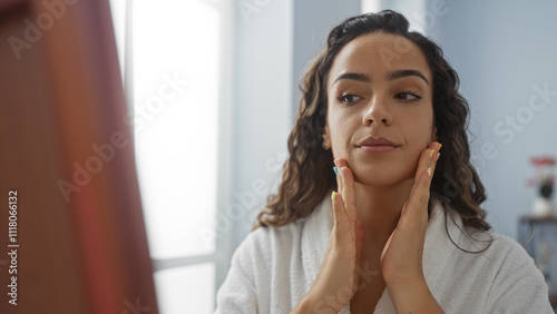 Woman in spa room applies face care product while wearing a robe indoors