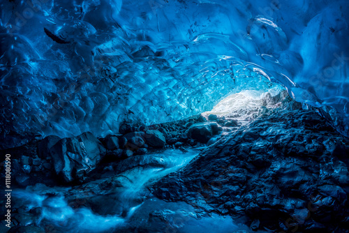 Entrance of an crystal blue ice cave with underground river inside Vatnajokull glacier, Iceland