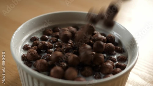 slow motion pouring chocolate choco cereal balls into an empty white bowl