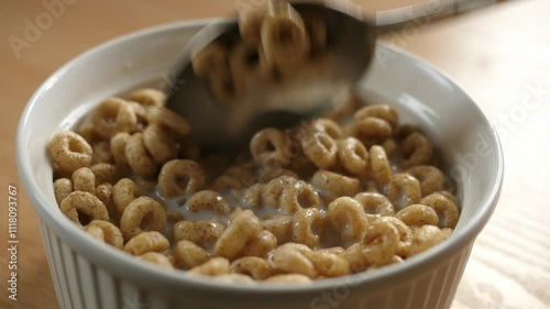 scooping honey cereal rings with a spoon from a bowl full of milk