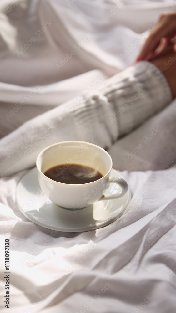 White cup of steaming coffee placed on saucer on bed with white bedding, creating cozy and inviting atmosphere. Concept of wake up, beauty, weekend, morning routine. White cup of steaming coffee placed on saucer on bed with white bedding, creating cozy and inviting atmosphere. Concept of wake up, beauty, weekend, morning routine.