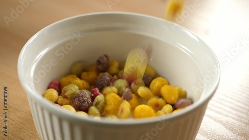 slow motion pouring colorful fruity cereal into an empty white bowl 