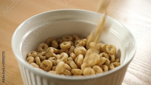 slow motion pouring honey cereal circles rings into an empty white bowl