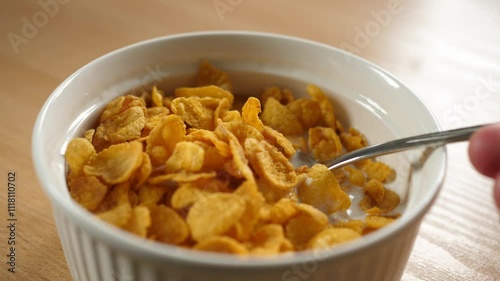 slow motion scooping cornflakes cereal with a spoon from a bowl full of milk