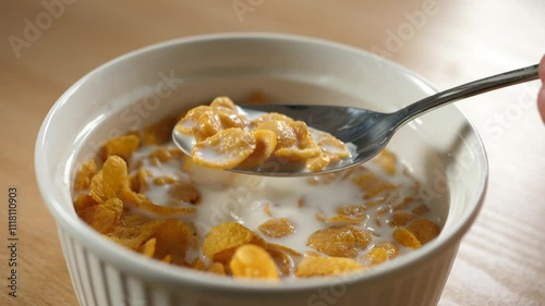 scooping with spoon cornflakes cereal with a spoon from a bowl full of milk