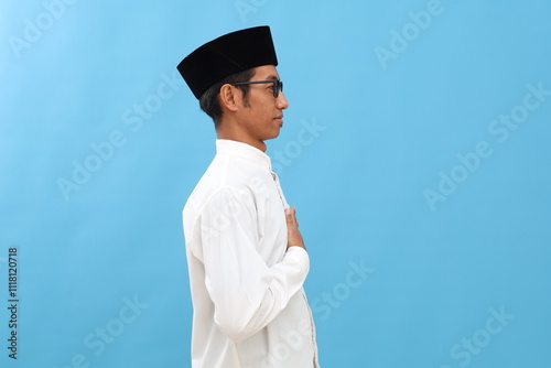 Young asian man wearing typical arab clothes isolated on blue background gazing left, sideways pose. photo