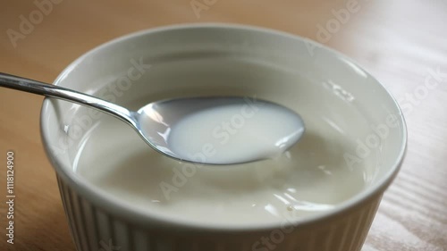 scooping milk with a spoon from a breakfast bowl full of milk