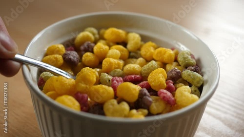 slow motion scooping colorful fruity cereal with a spoon from a bowl full of milk