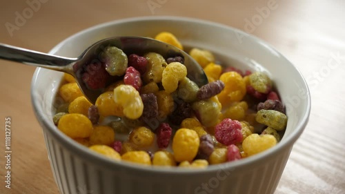 slow motion scooping colorful fruity cereal with a spoon from a bowl full of milk