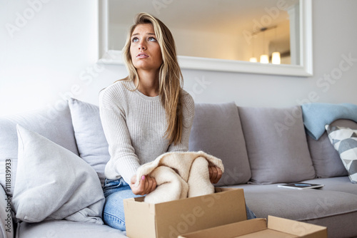 Thoughtful Woman Sitting on Sofa With Woolen Sweater and Cardboard Box