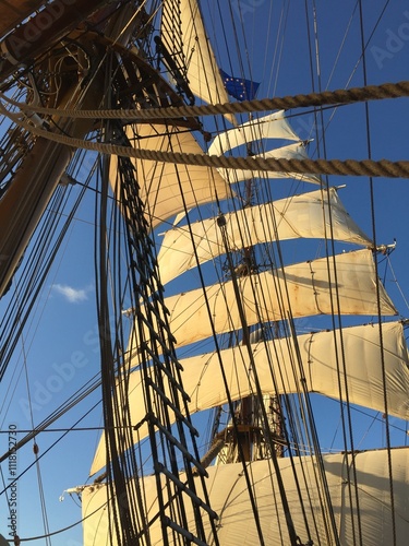 Sun hitting the white sails on a fully rigged ship 