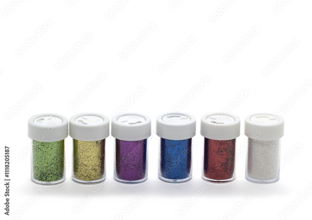 A row of colourful craft glitter in small jars on a white back ground. A row of colourful craft glitter in small jars on a white back ground.