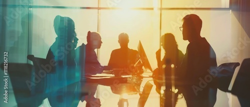 A team meeting is silhouetted against a vibrant sunset, symbolizing unity and brainstorming. photo