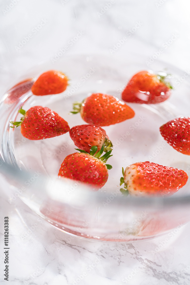 Preparing Strawberries in a Glass Mixing Bowl with Water Preparing Strawberries in a Glass Mixing Bowl with Water
