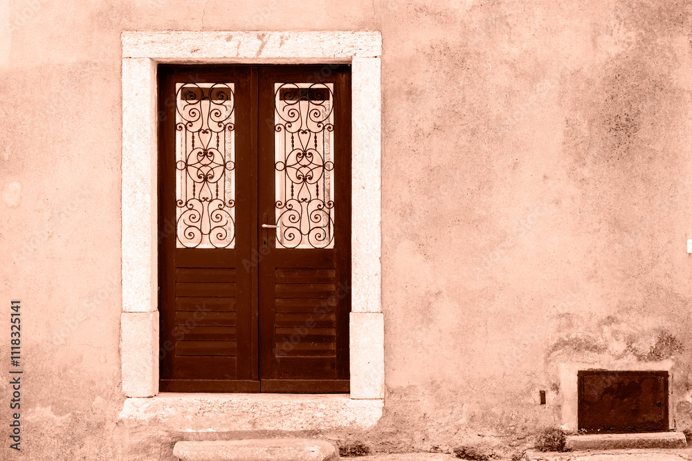 Fototapeta premium Old brown wooden door with ornament on the wall. Demonstrating color of the year 2025 - Mocha Mousse