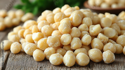 Fresh natural macadamia nuts piled on wooden surface, showcasing their creamy texture and light color, perfect for healthy snacking or culinary use