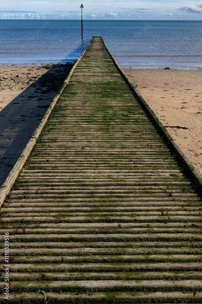 Fototapeta premium Wooden jetty leading out to sea on beach