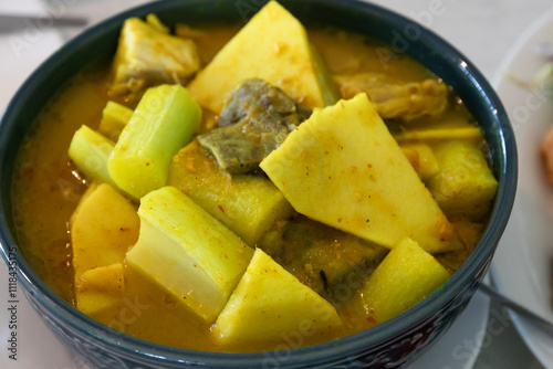 Yellow curry with fish, bamboo shoot and green taro (aaw dip) Thai Southern style food on wooden table. photo