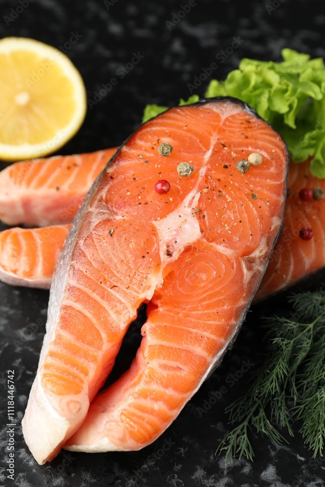 Fresh raw salmon steaks with spices, lemon, lettuce and dill on dark textured table, closeup Fresh raw salmon steaks with spices, lemon, lettuce and dill on dark textured table, closeup