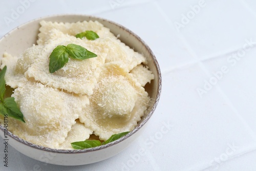 Delicious ravioli with cheese and basil on white tiled table, closeup. Space for text