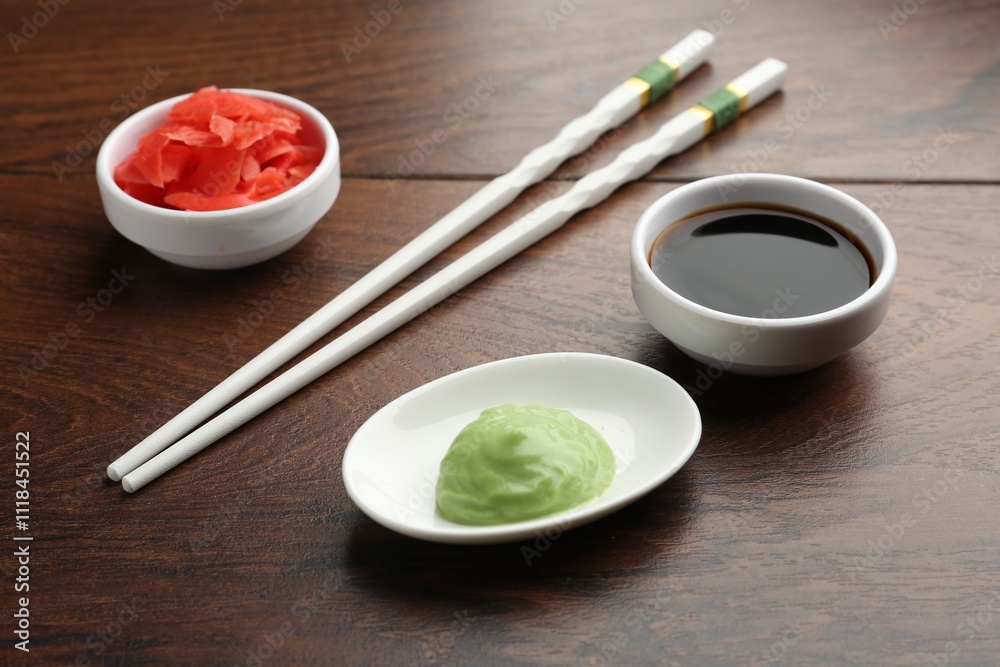 Hot wasabi paste, soy sauce, ginger and chopsticks on wooden table, closeup Hot wasabi paste, soy sauce, ginger and chopsticks on wooden table, closeup
