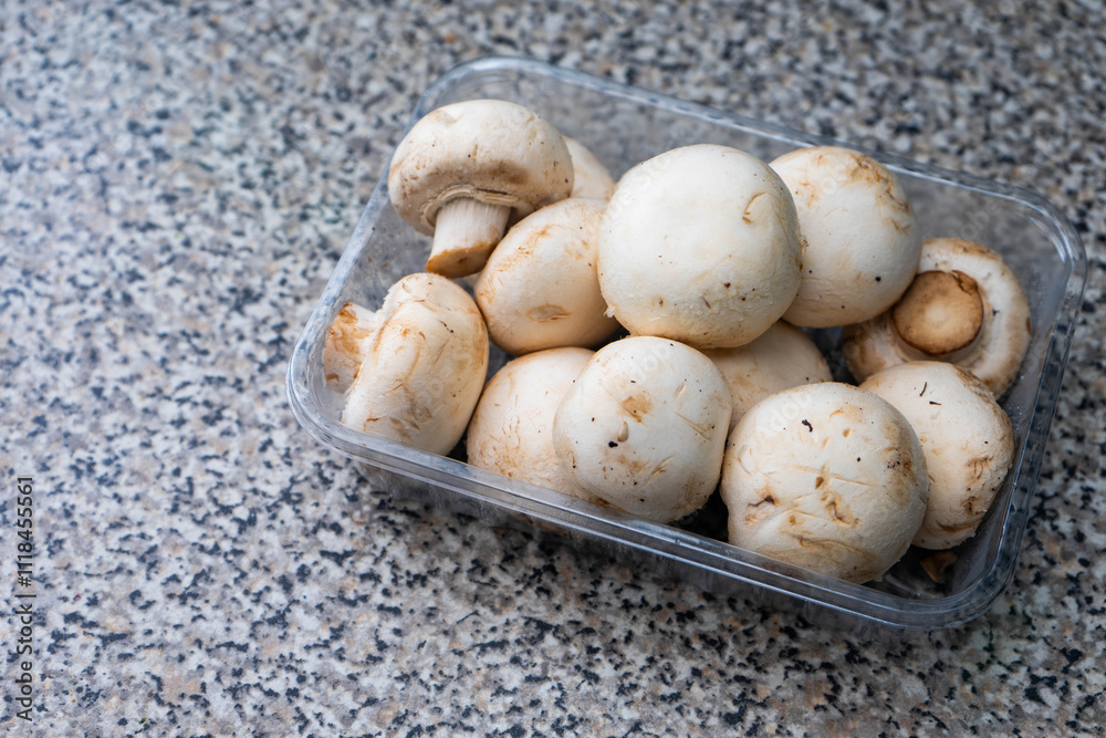 A close-up of a box filled with fresh white mushrooms, perfect for culinary or food-related content. A close-up of a box filled with fresh white mushrooms, perfect for culinary or food-related content.