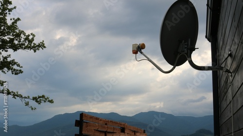 Foto silhouette of satellite dish hanging on wooden wall of house or cottage against