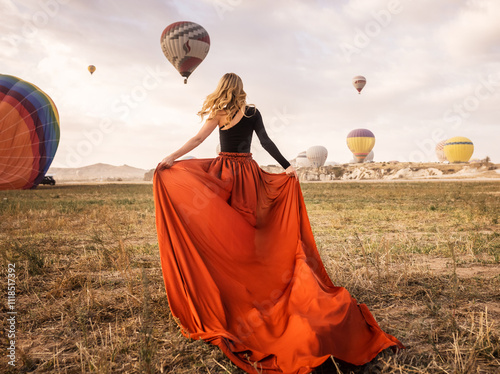 girl in long dress running towards balloons outdoors on summer day
 photo