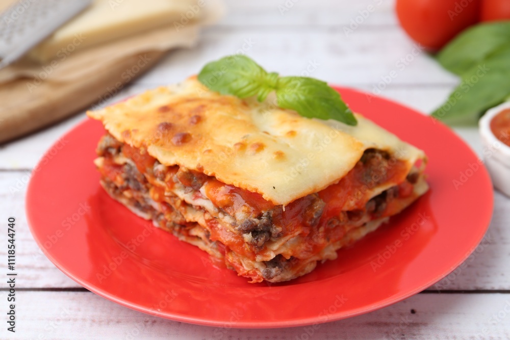 Piece of delicious cooked lasagna with basil on light wooden table, closeup Piece of delicious cooked lasagna with basil on light wooden table, closeup