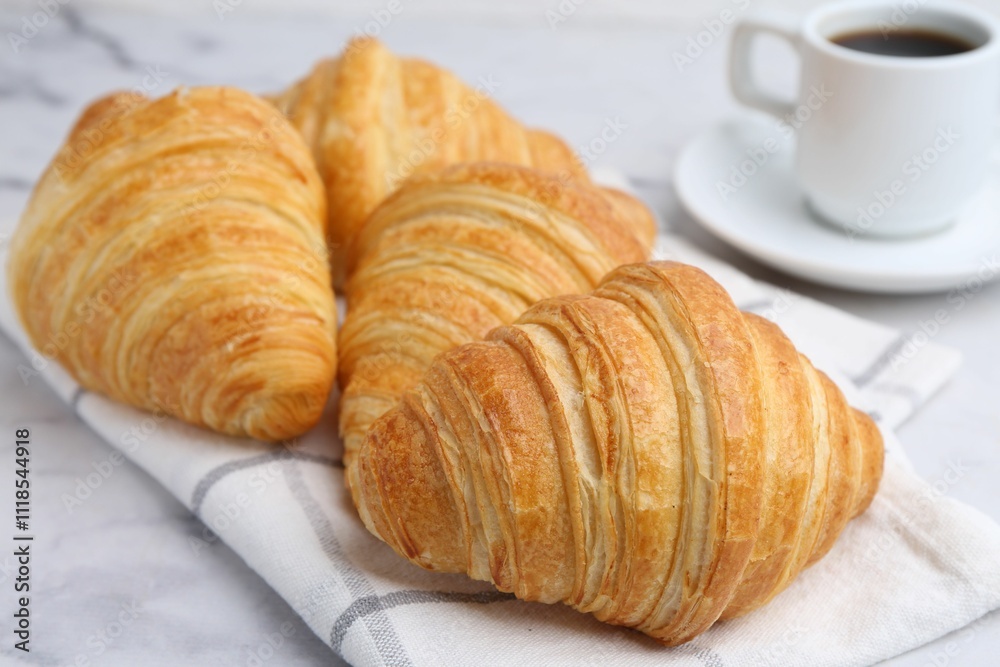 Tasty fresh croissants and cup of coffee on white marble table, closeup