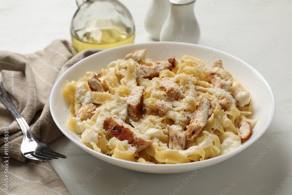 Tasty Alfredo pasta with chicken served on white marble table Tasty Alfredo pasta with chicken served on white marble table
