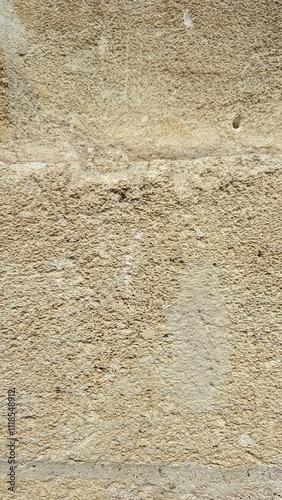 Close-up of a beige textured stone wall, showcasing its rough surface, natural imperfections, and timeless appeal, perfect for architectural or background design concepts.

