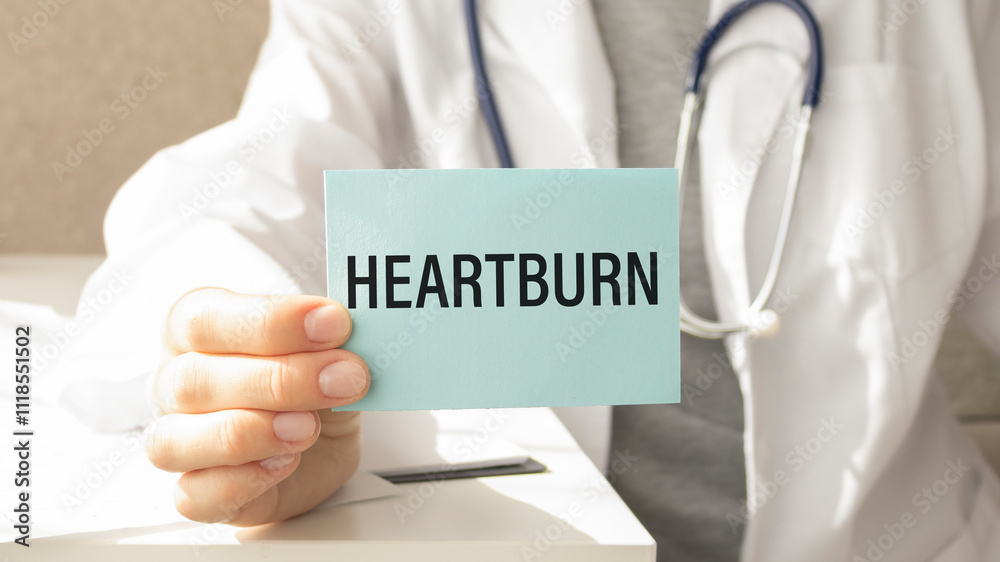 HEARTBURN written on a card in doctors hands HEARTBURN written on a card in doctors hands