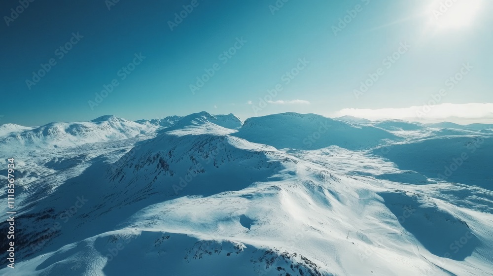 Obraz premium Drone view of mountains covered in the snow under the sunlight and a blue sky