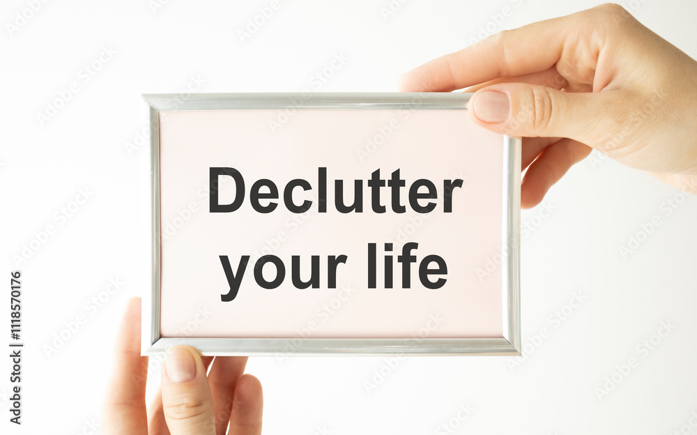Woman hands holding cardboard card with words Declutter Your Life made by black alphabet stamps. Woman hands holding cardboard card with words Declutter Your Life made by black alphabet stamps.