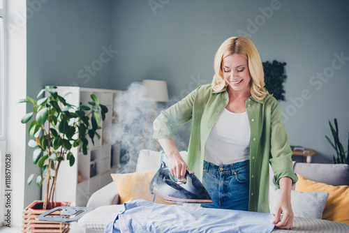 Bild auf Leinwand Middle-aged woman in casual outfit ironing at home with natural light in cozy li