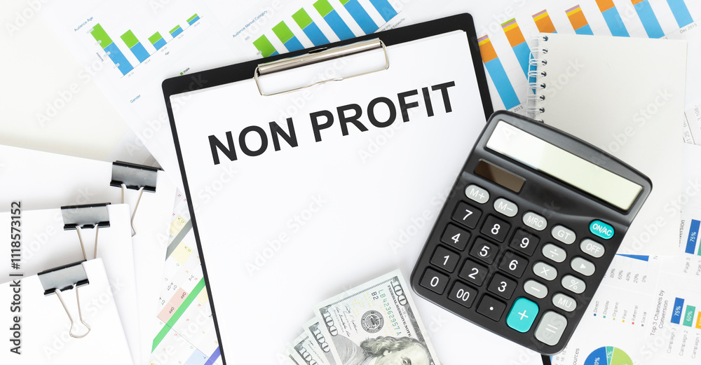NON PROFIT. TEXT ON WHITE PAPER ON BLACK ENVELOPE OVER THE FINANCIAL GRAPHICS AND THE CALCULATOR VIEW FROM ABOVE. CLOSE-UP. CAPITAL LETTERS BUSINESS CONCEPT NON PROFIT. TEXT ON WHITE PAPER ON BLACK ENVELOPE OVER THE FINANCIAL GRAPHICS AND THE CALCULATOR VIEW FROM ABOVE. CLOSE-UP. CAPITAL LETTERS BUSINESS CONCEPT