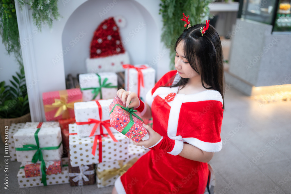 Portrait Cute Smiling asian girl in red santa with looking to the camera near Christmas greeting picture parcel decoration on Christmas tree background Decoration During Christmas and New Year.