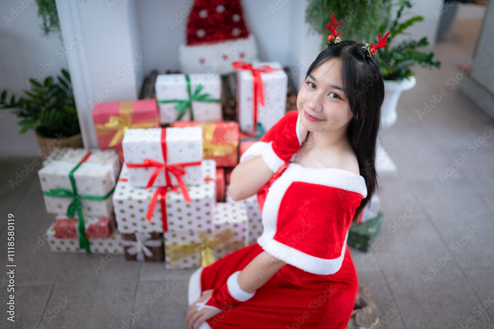 Portrait Cute Smiling asian girl in red santa with looking to the camera near Christmas greeting picture parcel decoration on Christmas tree background Decoration During Christmas and New Year.