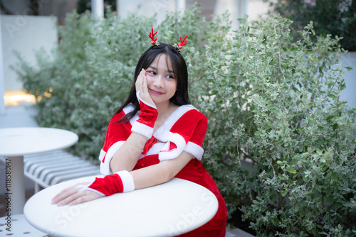 Obraz na płótnie Portrait Cute Smiling asian girl in red santa with looking to the camera near Christmas greeting picture parcel decoration on Christmas tree background Decoration During Christmas and New Year. w salonie
