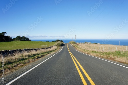 Empty road with the ocean in background on Otago Peninsula, New Zealand. This road leads to Sandfly Bay. 