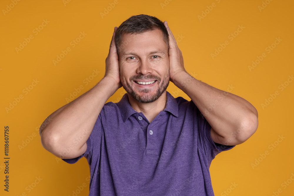 Man covering his ears on orange background Man covering his ears on orange background